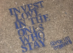 “Invest love in the ones who stay” is painted on a sidewalk in downtown Indianapolis. Boots has painted similar messages throughout the city for daily pedestrians.